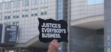Someone holding up a sign reading 'Justice is everybody's business'